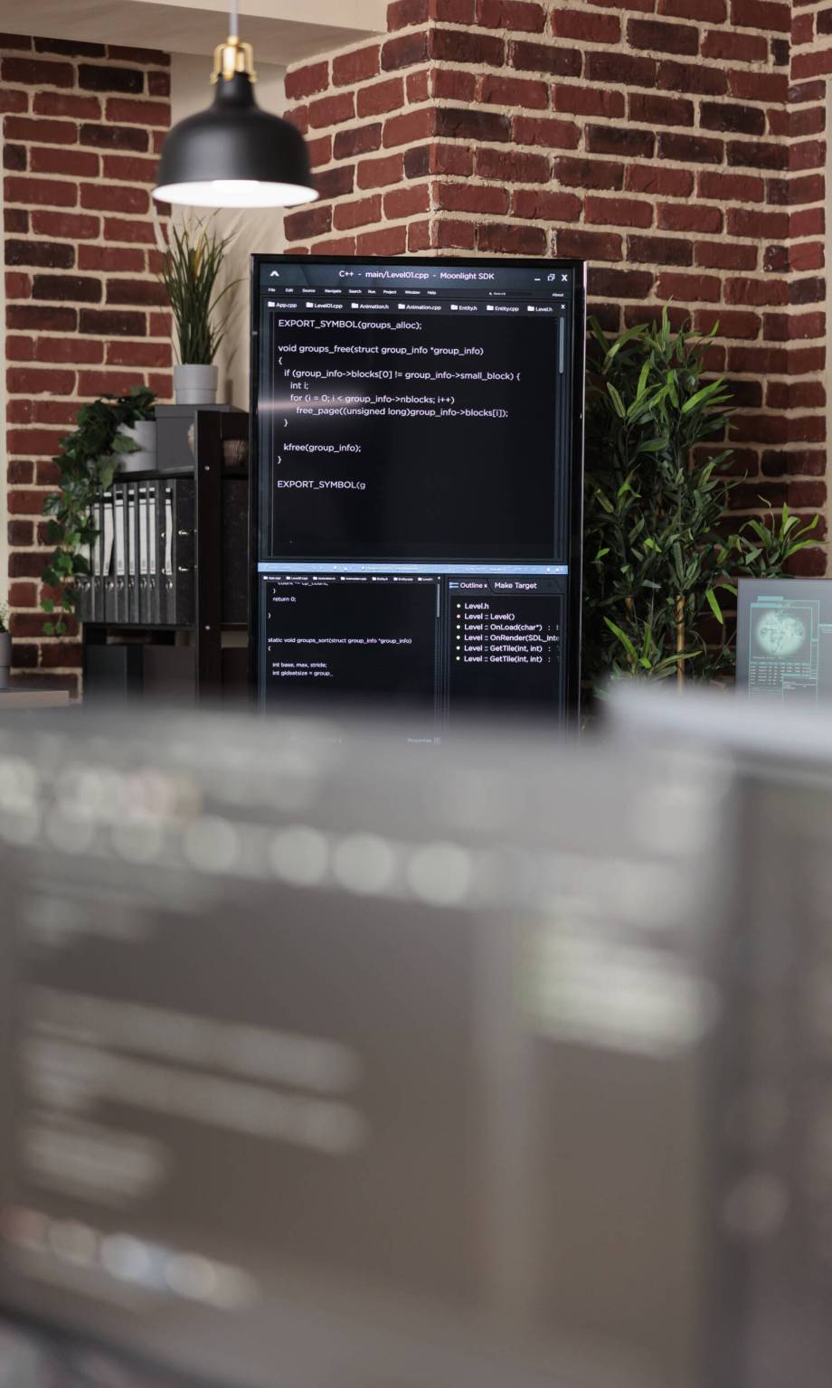 Interior of empty data center office with multiple computer screens showing programming line codes. Server room with modern brick wall interior and high quality hardware and software technology.